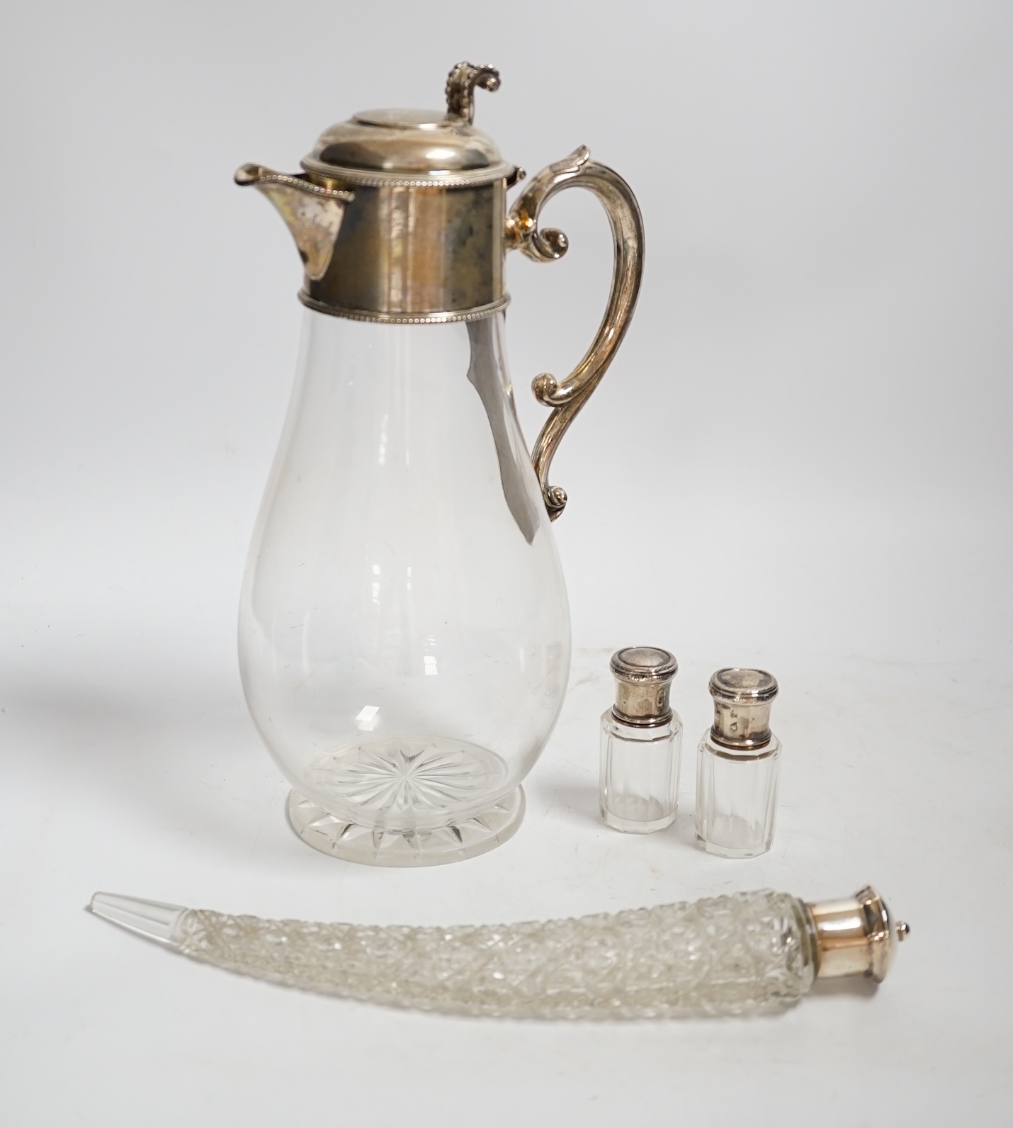 A Victorian silver mounted glass claret jug, W & G Sissons, Sheffield, 1879, 27.4cm, together with three mounted glass bottles, two with French white metal mounts.